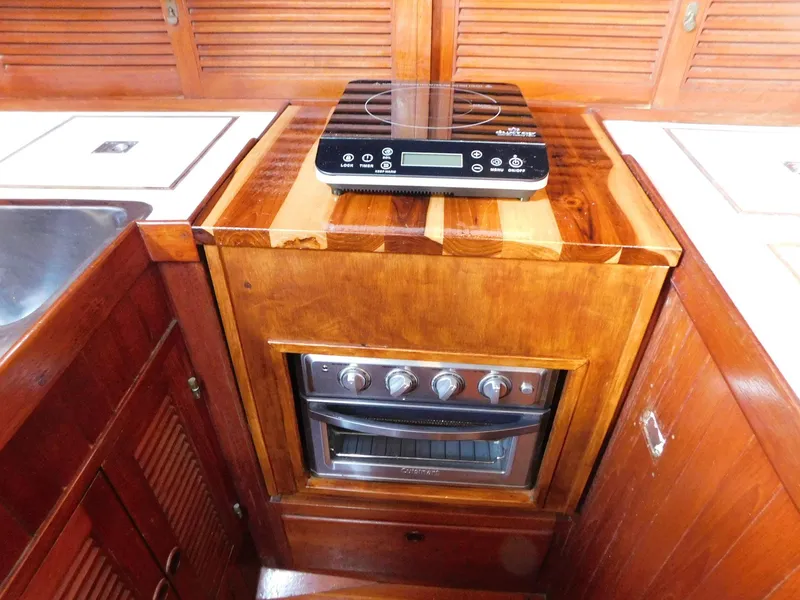 Slide: The Image of 1984 Tayana 37 yacht kitchen with wooden cabinetry and modern stove. - 10