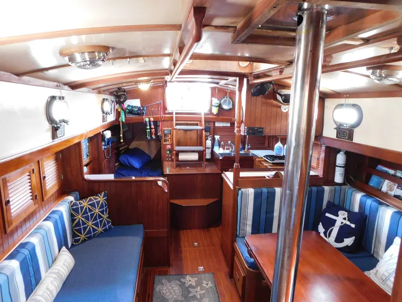 Slide: The Image of 1984 Tayana 37 sailboat interior with wood finish, blue cushions, and nautical decor. - 2