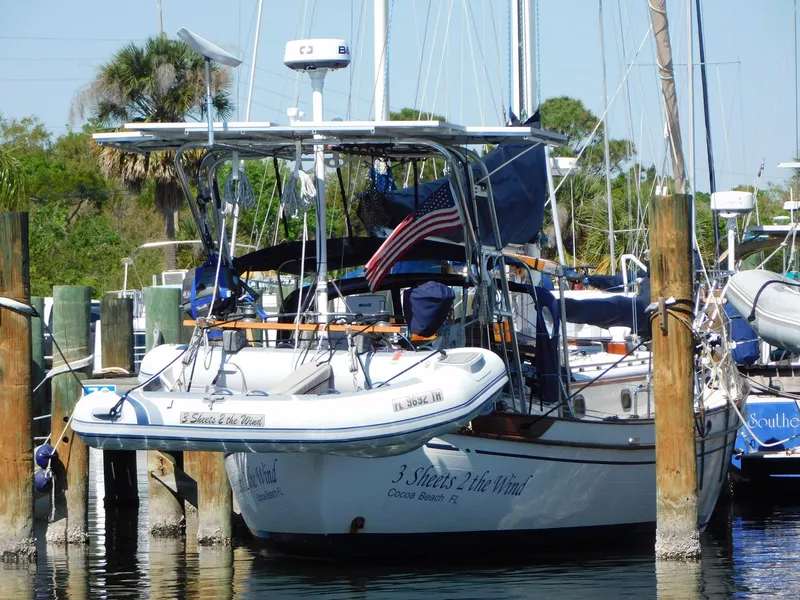 Slide: The Image of 1984 Tayana 37 sailboat docked with American flag and dinghy, surrounded by other boats. - 29