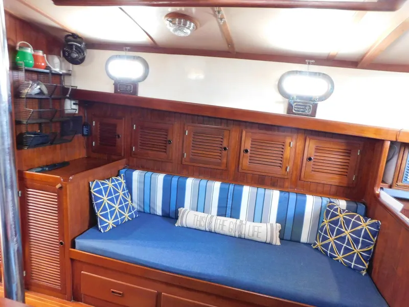 Slide: The Image of Cozy interior of 1984 Tayana 37 sailboat with blue-striped cushions and wooden cabinetry. - 4