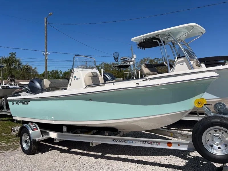 Slide: The Image of 2025 Key West 1720 Center Console boat on trailer, parked outdoors under clear blue sky. - 2