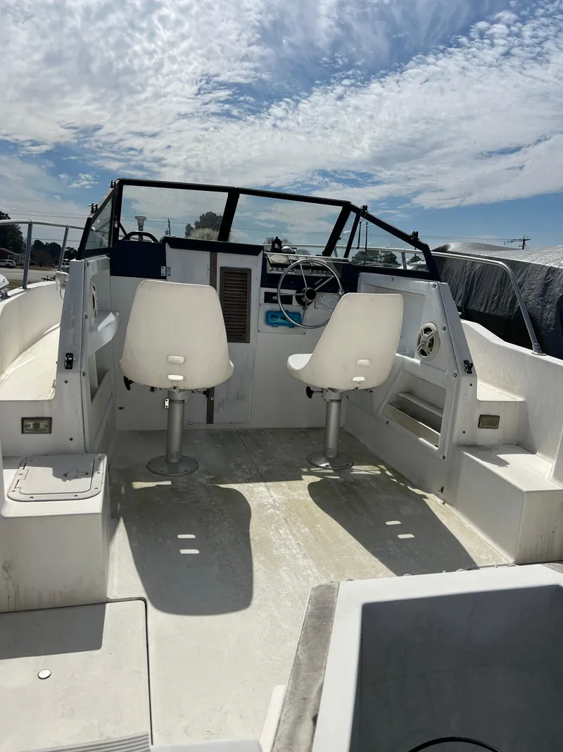 Slide: The Image of 1995 Bayliner Trophy 20 boat interior with dual white seats and steering wheel under a blue sky. - 3