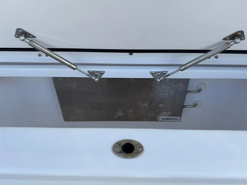 Slide: The Image of Open storage compartment of 2022 Everglades 395cc boat with metal hinges. - 25