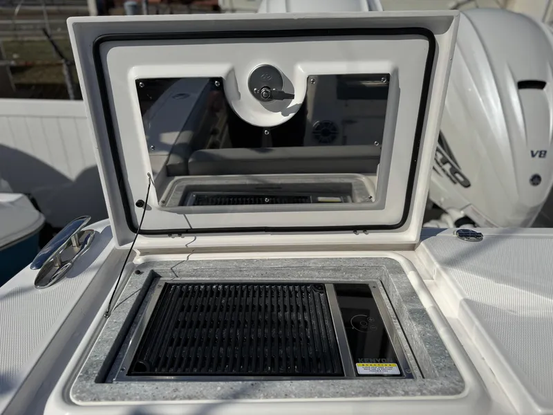 Slide: The Image of 2022 Everglades 395cc boat grill compartment with open lid and visible engine. - 26