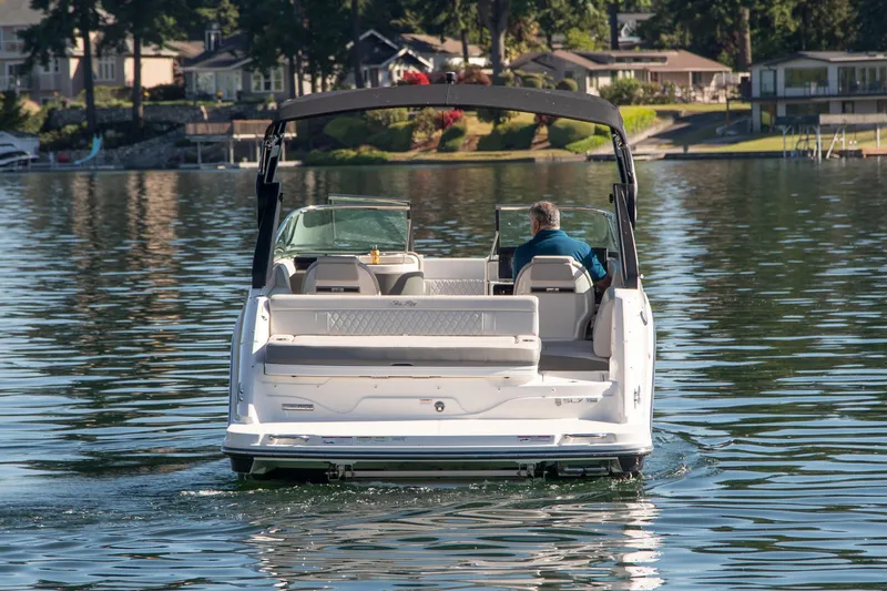 Slide: The Image of 2020 Sea Ray SLX 250 boat cruising on a calm lake near shoreline homes. - 5