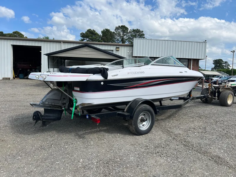 Slide: The Image of 2008 Four Winns H180 boat on trailer, parked outside a garage under a cloudy sky. - 4