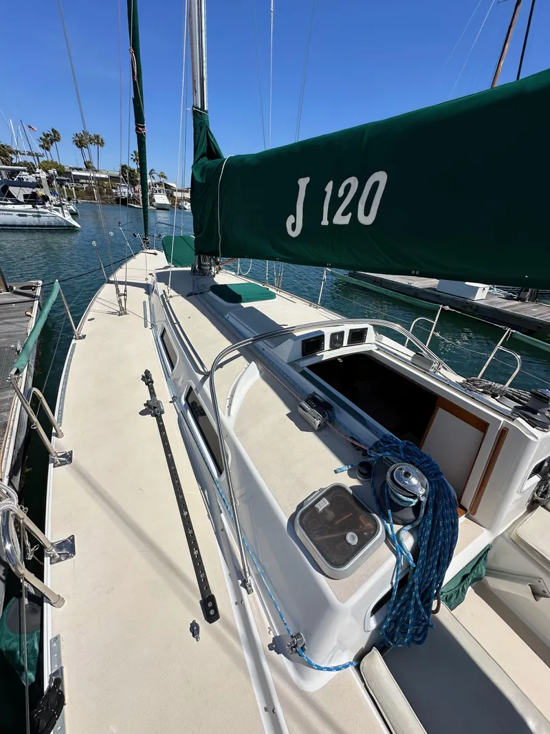 Slide: The Image of 1996 J Boats J/120 sailboat docked, featuring green sail cover and spacious deck. - 11