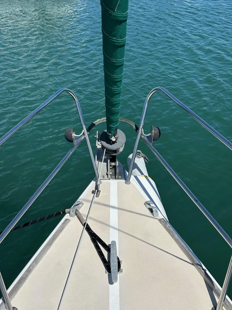 Slide: The Image of Bow of 1996 J Boats J/120 sailboat with green sail cover on calm water. - 15