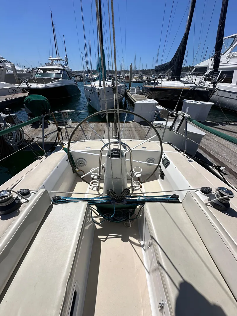 Slide: The Image of 1996 J Boats J/120 sailboat docked in a marina, showcasing cockpit and steering wheel. - 24