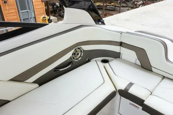 Slide: The Image of 2016 Yamaha Boats 242 Limited S E-Series interior with white and gray seating, speaker, and cup holder. - 29