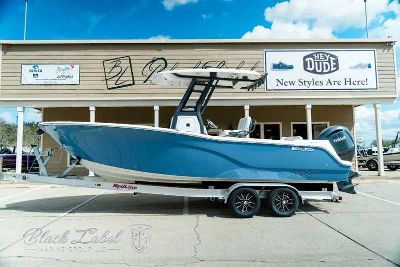 The Image of 2025 Sea Fox 248 Commander boat on trailer, parked outside a store with signage. - 0