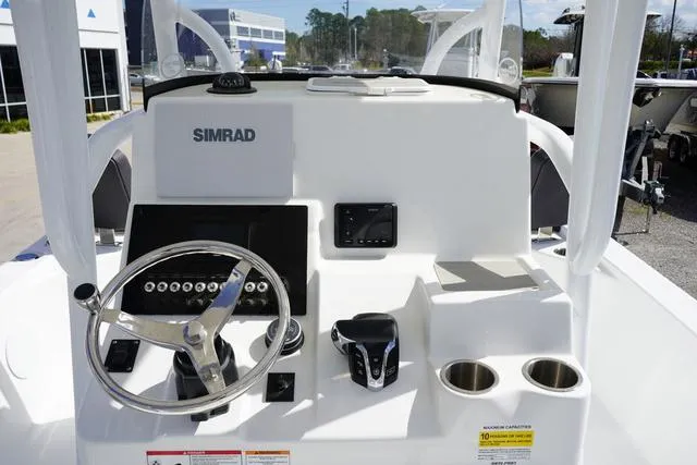 Slide: The Image of 2025 Sea Pro 250 Bay boat console with steering wheel, Simrad display, and cup holders. - 12