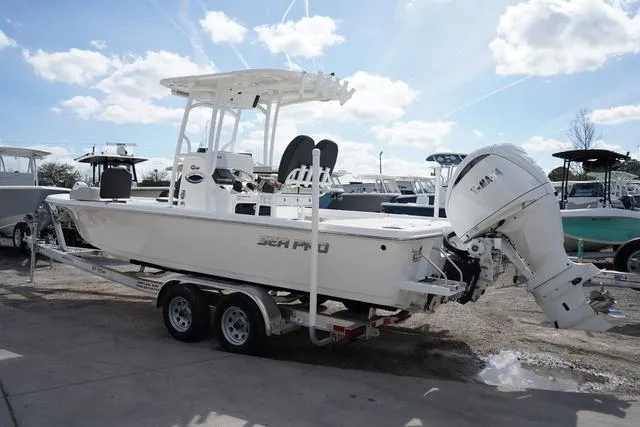 Slide: The Image of 2025 Sea Pro 250 Bay boat on trailer, featuring Yamaha outboard motor, under a sunny sky. - 2