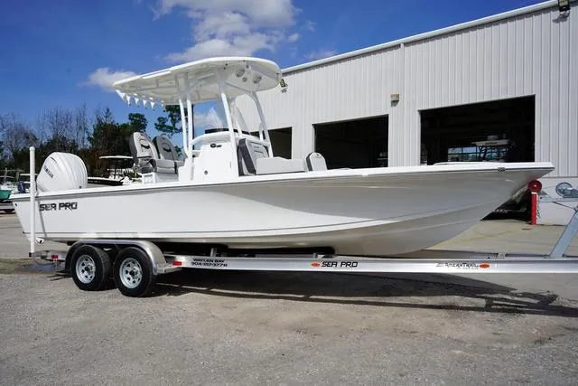 Slide: The Image of 2025 Sea Pro 250 Bay boat on trailer, parked outside a warehouse. - 4