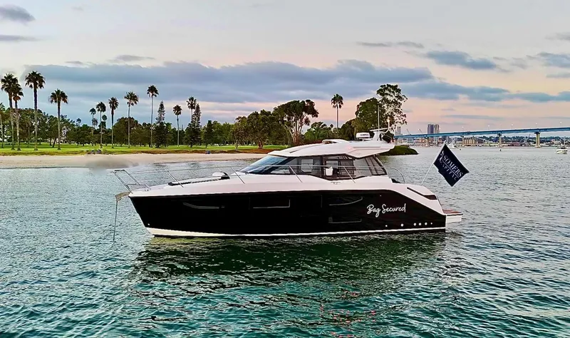 Slide: The Image of 2023 Bavaria SR36 yacht cruising near a scenic shoreline with palm trees. - 0