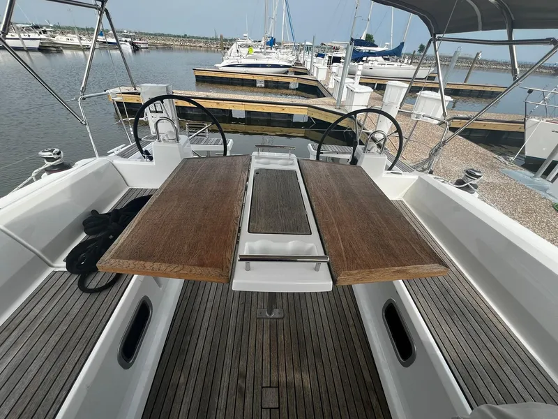 Slide: The Image of Beneteau Oceanis 38.1 sailboat cockpit with wooden table, dual steering wheels, docked in marina. - 9