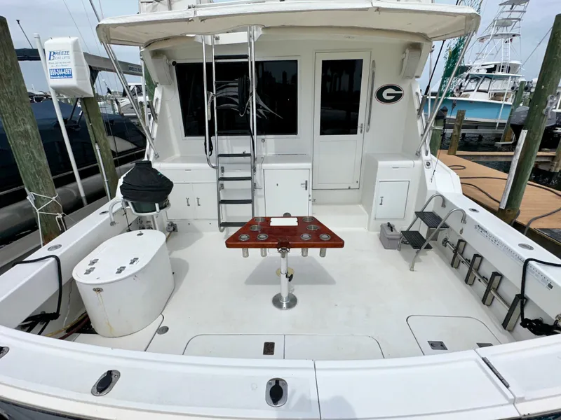 Slide: The Image of 1994 Hatteras 46 Convertible yacht deck with fishing setup and seating area. - 10