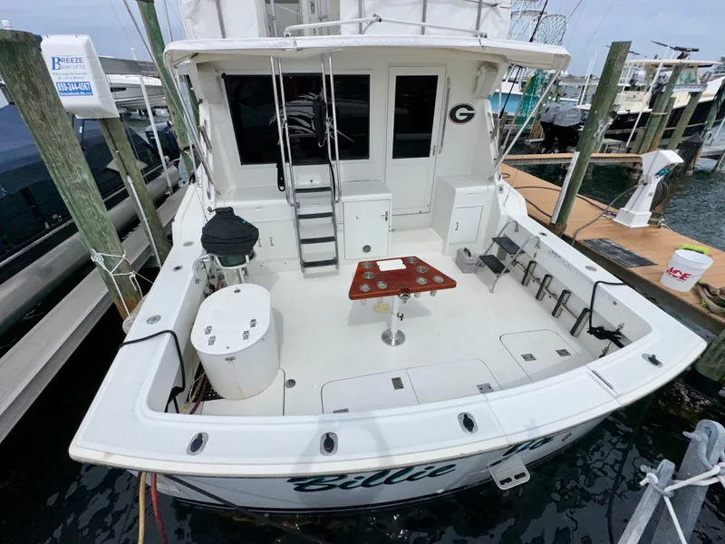 Slide: The Image of 1994 Hatteras 46 Convertible yacht docked, featuring spacious deck and fishing equipment. - 11