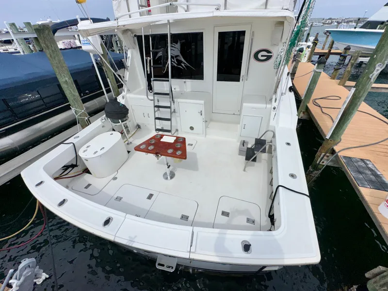 Slide: The Image of 1994 Hatteras 46 Convertible yacht docked, featuring spacious deck and fishing setup. - 8