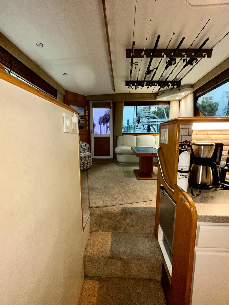 Slide: The Image of Interior of a 1994 Hatteras 46 Convertible yacht with cozy seating and fishing rods. - 83