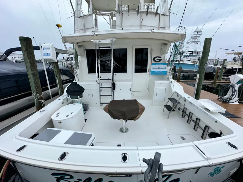 Slide: The Image of 1994 Hatteras 46 Convertible yacht docked, featuring spacious deck and fishing equipment. - 9