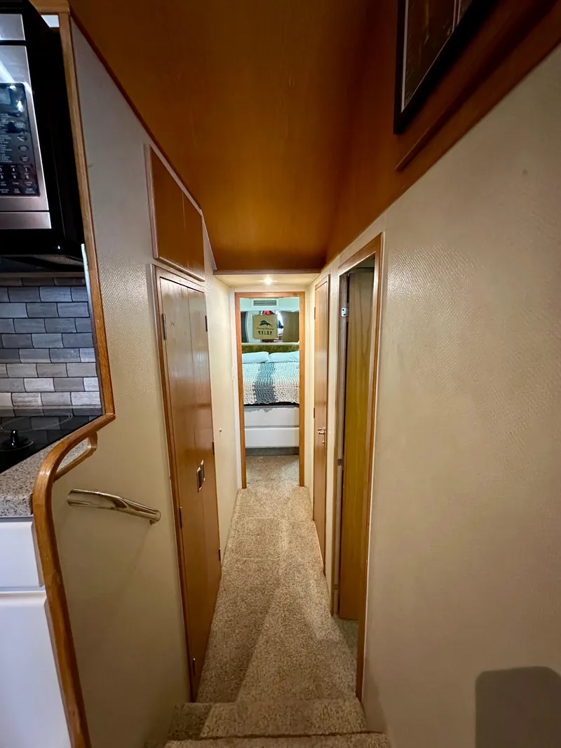 Slide: The Image of Interior hallway of 1994 Hatteras 46 Convertible yacht, featuring wood paneling and carpeted flooring. - 98