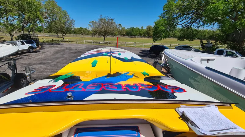 Slide: The Image of Cigarette Tiger 42 boat, vibrant design, parked outdoors, surrounded by trees and vehicles. - 6