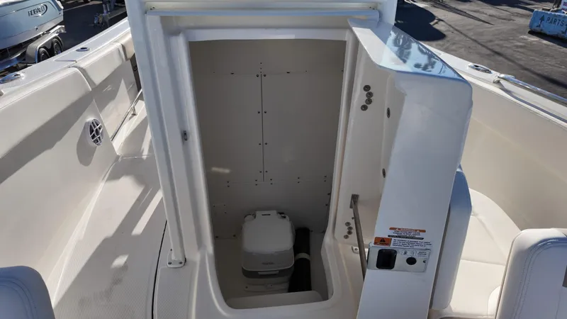 Slide: The Image of 2025 Robalo R230 boat interior with open storage compartment and portable toilet. - 12