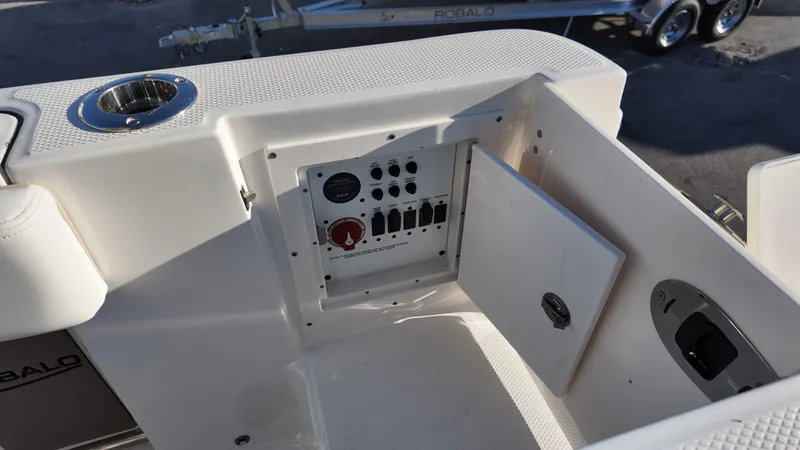 Slide: The Image of Control panel on a 2025 Robalo R230 boat, featuring switches and a cup holder. - 14
