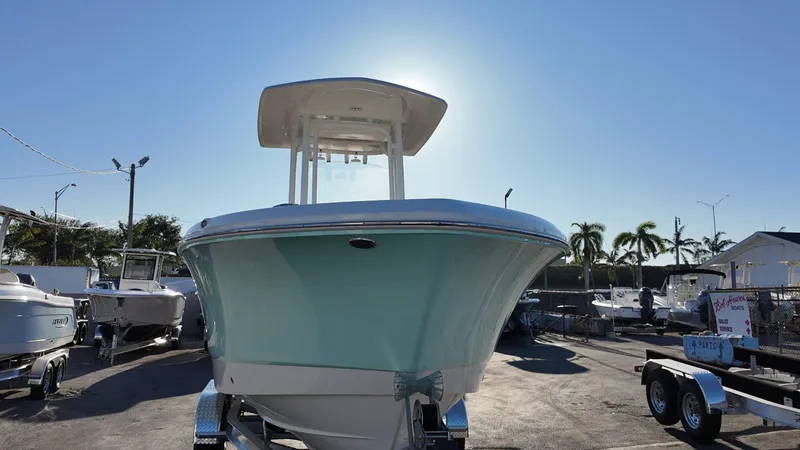 Slide: The Image of 2025 Robalo R230 boat in a sunny marina, front view with palm trees in background. - 3