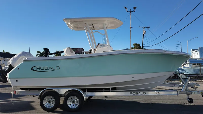 Slide: The Image of 2025 Robalo R230 boat on trailer, light blue hull, clear sky background. - 4