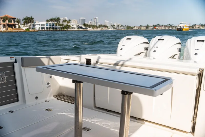 Slide: The Image of 2021 Pursuit 428 boat deck with table and Yamaha V8 engines, coastal view. - 11