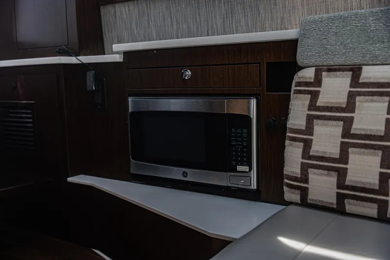 Slide: The Image of Modern kitchen area in 2021 Pursuit 428 boat with microwave and patterned seating. - 16