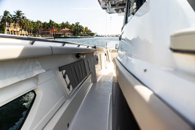 Slide: The Image of 2021 Pursuit 428 boat side view on a sunny day near palm-lined waterfront. - 3