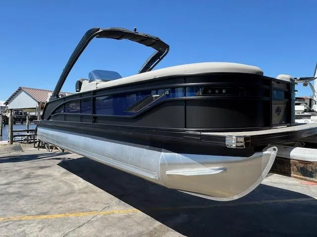 Slide: The Image of 2025 Barletta CORSA 25MA pontoon boat with sleek black design, docked under clear blue sky. - 4