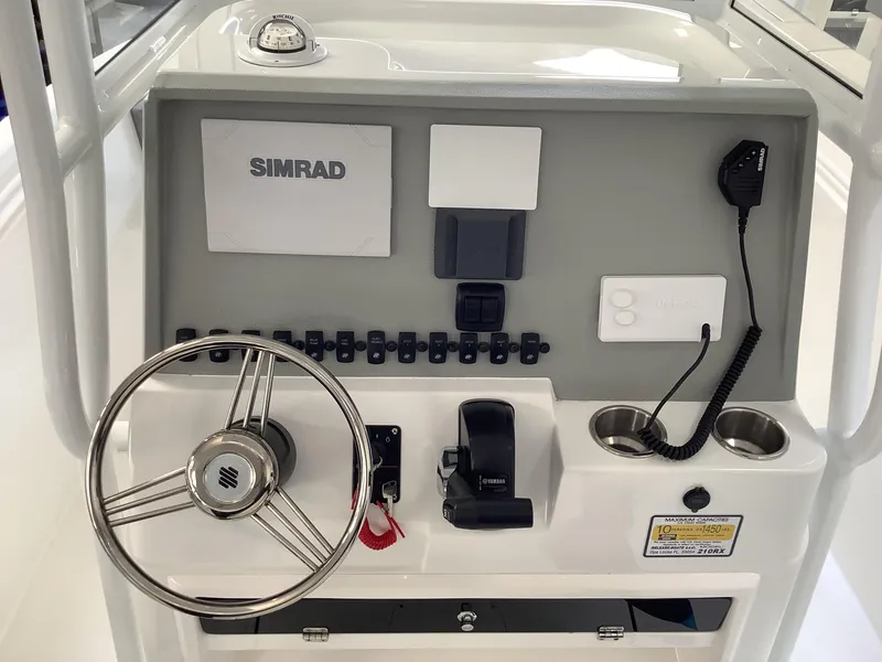 Slide: The Image of 2025 Release 210RX Center Console boat dashboard with steering wheel and Simrad electronics. - 12