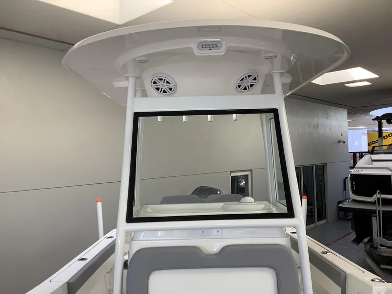 Slide: The Image of 2025 Release 210RX Center Console boat with T-top and speakers in showroom. - 18