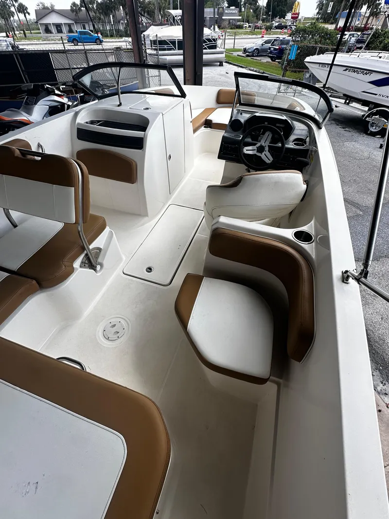 Slide: The Image of 2021 Bayliner VR6 Bowrider OB interior with seating and steering wheel, parked in a showroom. - 22