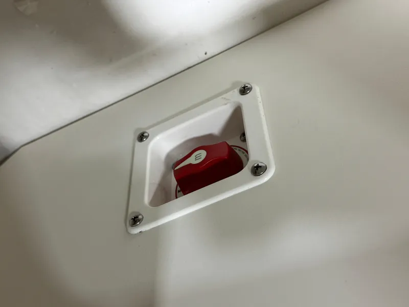 Slide: The Image of Battery switch on 2025 Chaparral 21 SSi boat, featuring a red knob and white panel. - 13