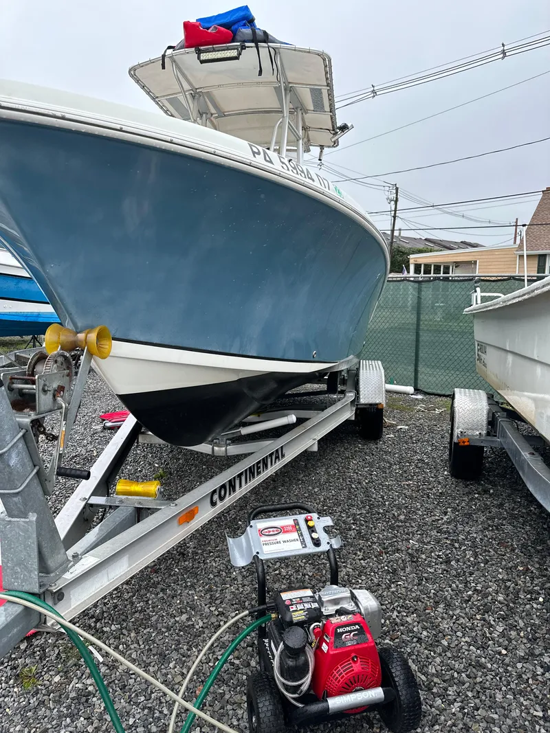 Slide: The Image of 2009 Sailfish 218 CC boat on trailer, parked outdoors, with a pressure washer nearby. - 13