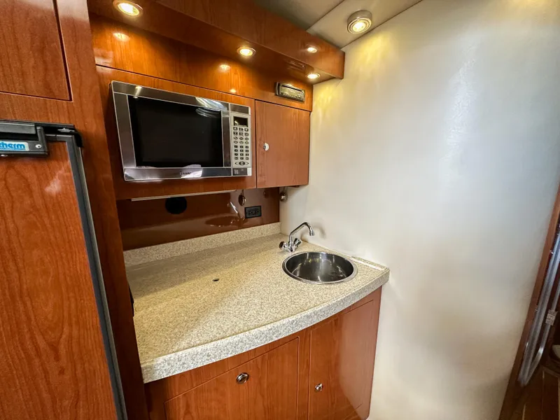 Slide: The Image of 2007 Regal Commodore 3760 IO yacht kitchenette with microwave, sink, and wooden cabinetry. - 19