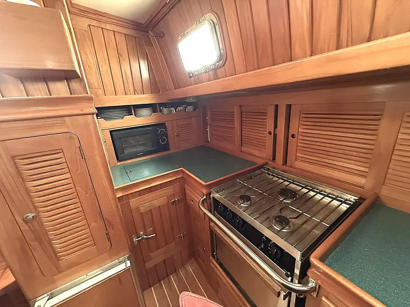 Slide: The Image of Cabo Rico 2000 yacht kitchen with wood cabinetry, stove, and microwave. - 13
