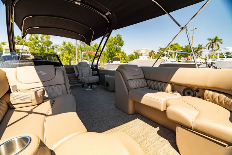 Slide: The Image of 2022 Bennington LX 24 Swingback boat interior with tan seating and canopy. - 2