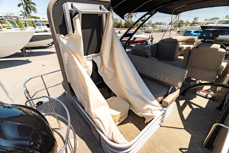 Slide: The Image of 2022 Bennington LX 24 Swingback boat interior with seating and canopy, docked outdoors. - 45