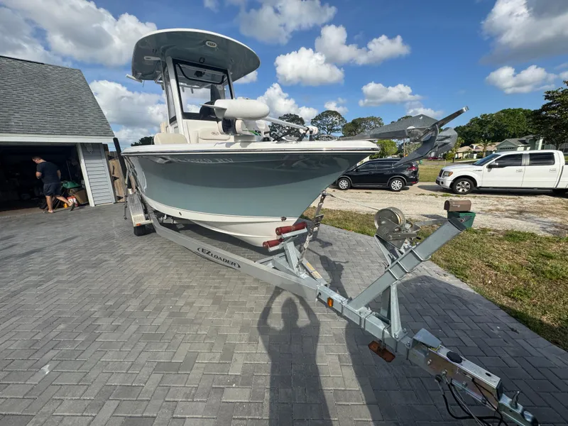 Slide: The Image of 2019 Sea Hunt 235 SE boat on trailer, parked on paved driveway under blue sky. - 14