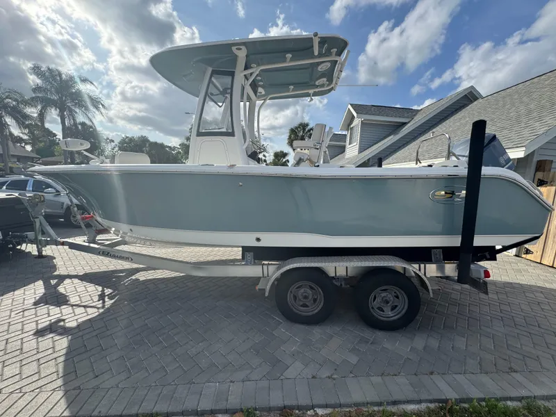 Slide: The Image of 2019 Sea Hunt 235 SE boat on trailer, parked in driveway under cloudy sky. - 23