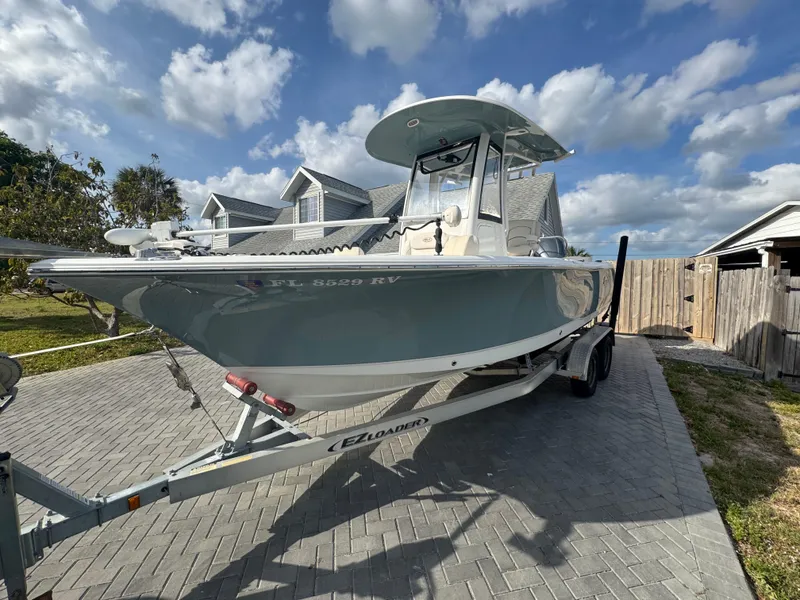 Slide: The Image of 2019 Sea Hunt 235 SE boat on trailer, parked on a paved driveway under a cloudy sky. - 24