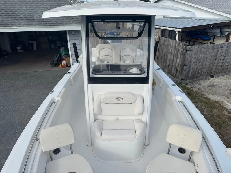 Slide: The Image of 2019 Sea Hunt 235 SE boat with white seating and console, parked in a driveway. - 45