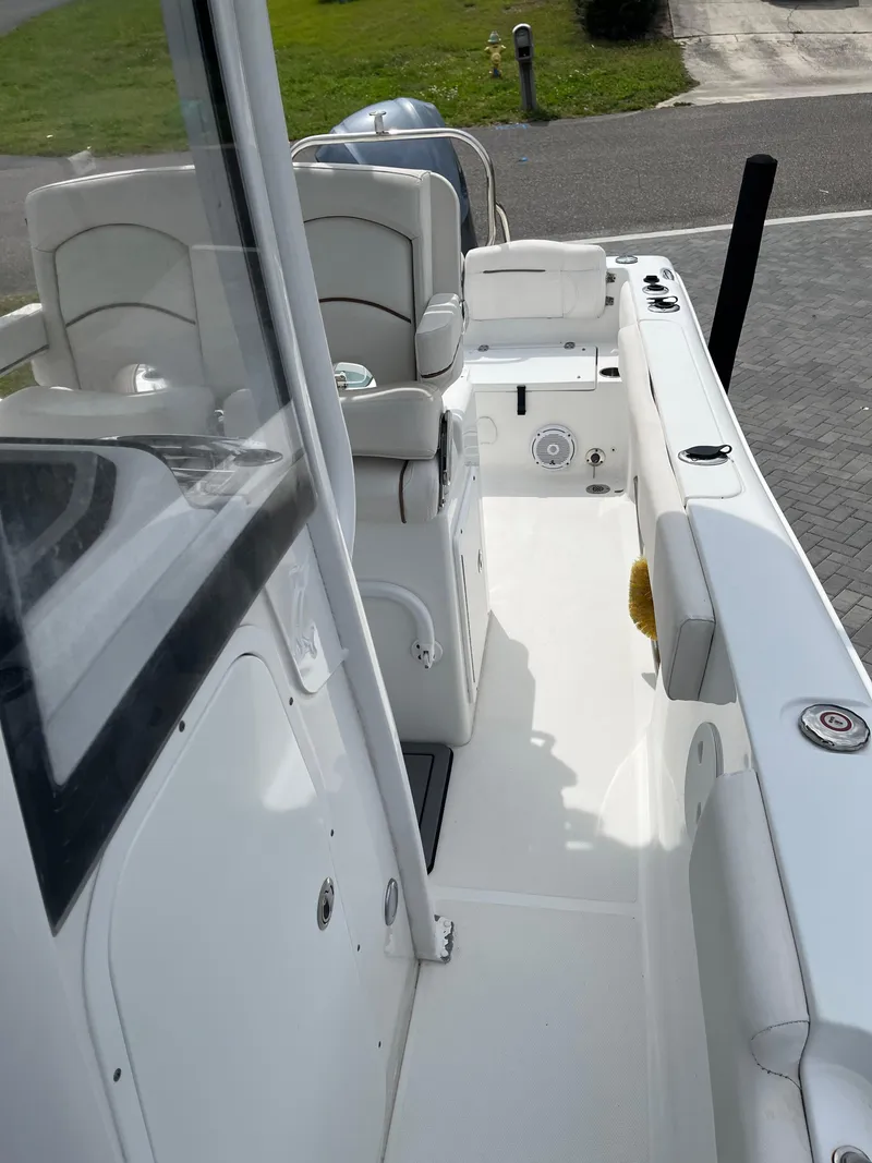 Slide: The Image of 2019 Sea Hunt 235 SE boat interior with seating and console, docked on a sunny day. - 9