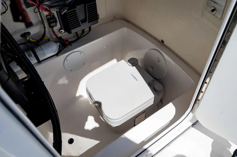 Slide: The Image of Interior of 2015 Edgewater 240 Inshore boat featuring a compact portable toilet. - 33